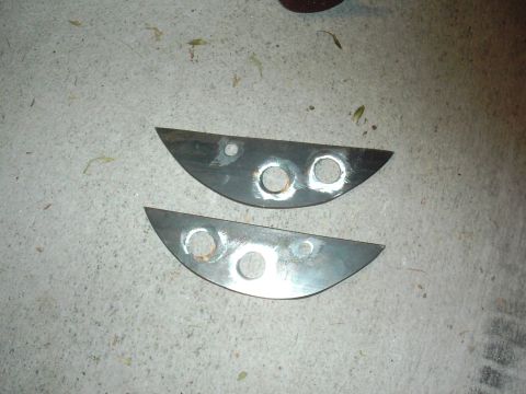 1978 Ford Bronco - Two custom metal brackets with drilled holes are shown on a concrete surface.