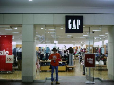 1988 Ford Bronco - A man wearing an orange shirt and cowboy hat stands in front of a Gap store entrance.