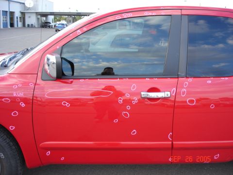2005 Nissan Titan - This red truck has numerous dents marked with white circles and lines, indicating hail damage.