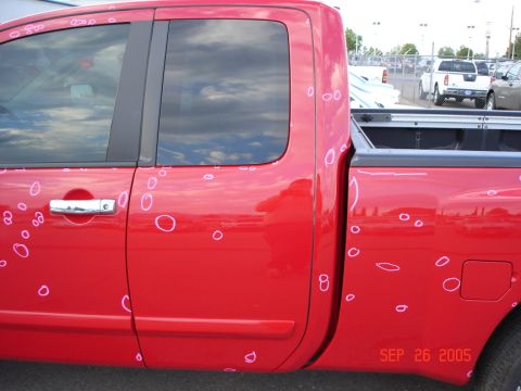 2005 Nissan Titan - A red pickup truck shows many dents marked with pink circles on its side panels and bed.