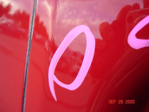 2005 Nissan Titan - A close-up shows pink markings on a red vehicle's surface, with a date stamp visible.