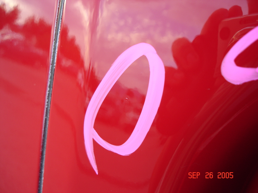 Close-up of a red car door with pink markings and a date stamp