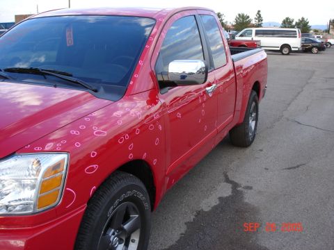 2005 Nissan Titan - Red pickup truck with numerous dents circled in pink, indicating hail damage.