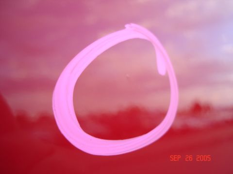 2005 Nissan Titan - A pink circle is drawn on the red painted surface of a vehicle, with a date and website visible.