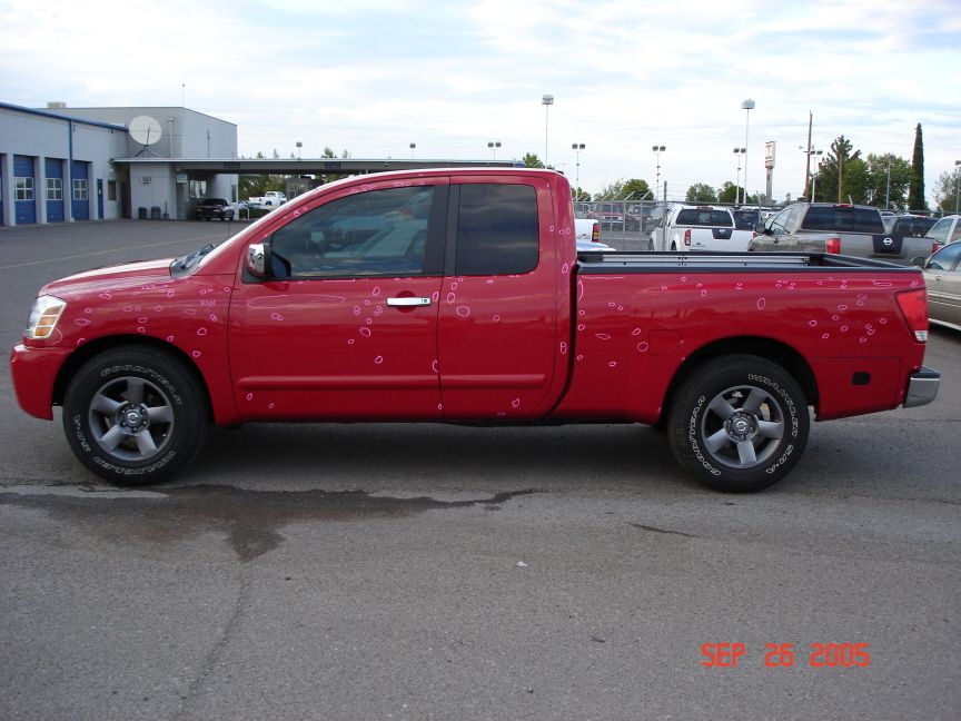 Red Nissan Titan side profile with hail damage circled in pink marker