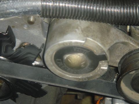 1986 Ford Mustang - A close-up view of a vehicle's engine belt tensioner assembly, showing part markings.