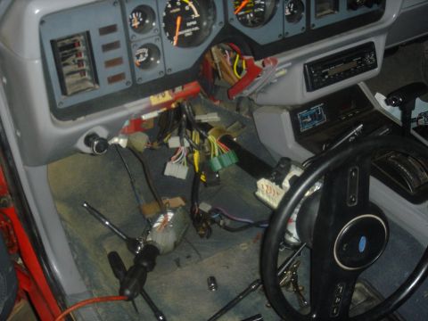 1986 Ford Mustang - The dashboard of a car is disassembled, revealing a complex network of wires and components.