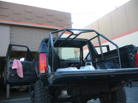 1992 Ford Bronco - Rear three-quarter view of a black Ford Bronco with the hardtop, tailgate glass and rear interior removed, revealing a freshly welded black…