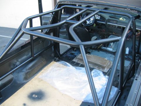 1992 Ford Bronco - View down into a gutted Ford truck cab with a freshly welded and painted multi-point roll cage tied into the door bars and A-pillars. Carpe…