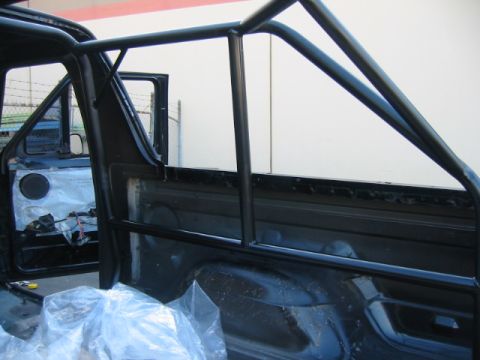 1992 Ford Bronco - Roll cage installed inside a vehicle's interior, with the door open.