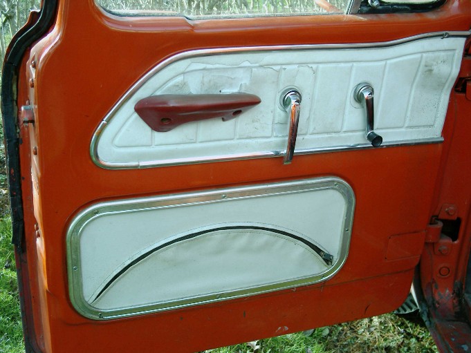 Orange and white vintage truck interior door panel with red door handle, chrome window crank and map pocket