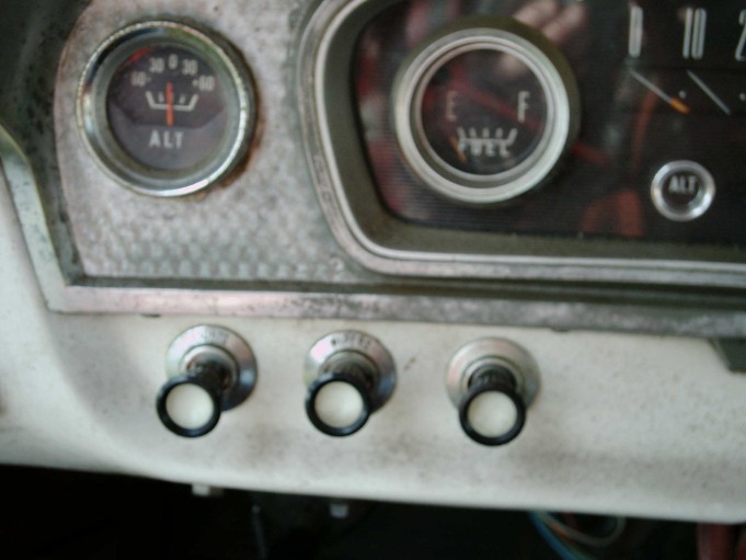 Close-up of vintage truck dash with ALT amp gauge, round fuel gauge and three white-knob pull switches