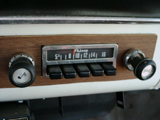 Vintage Jeep AM radio with woodgrain dash trim, tuning and volume knobs and five chrome preset buttons
