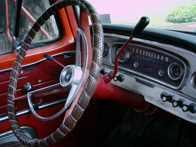 Vintage Ford pickup interior: laced red steering wheel, column shifter and painted metal dash