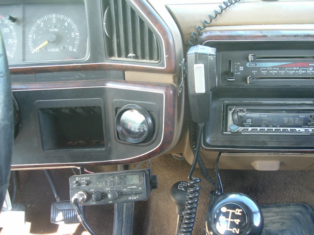 Dash of a vehicle with Cobra CB radio, Kenwood stereo showing 97.3, tachometer, and manual shift knob