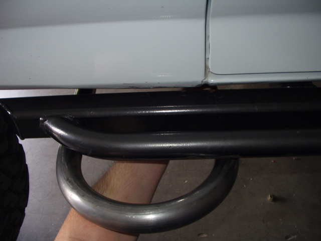 Black tubular rear bumper or step bar mounted under a gray vehicle body