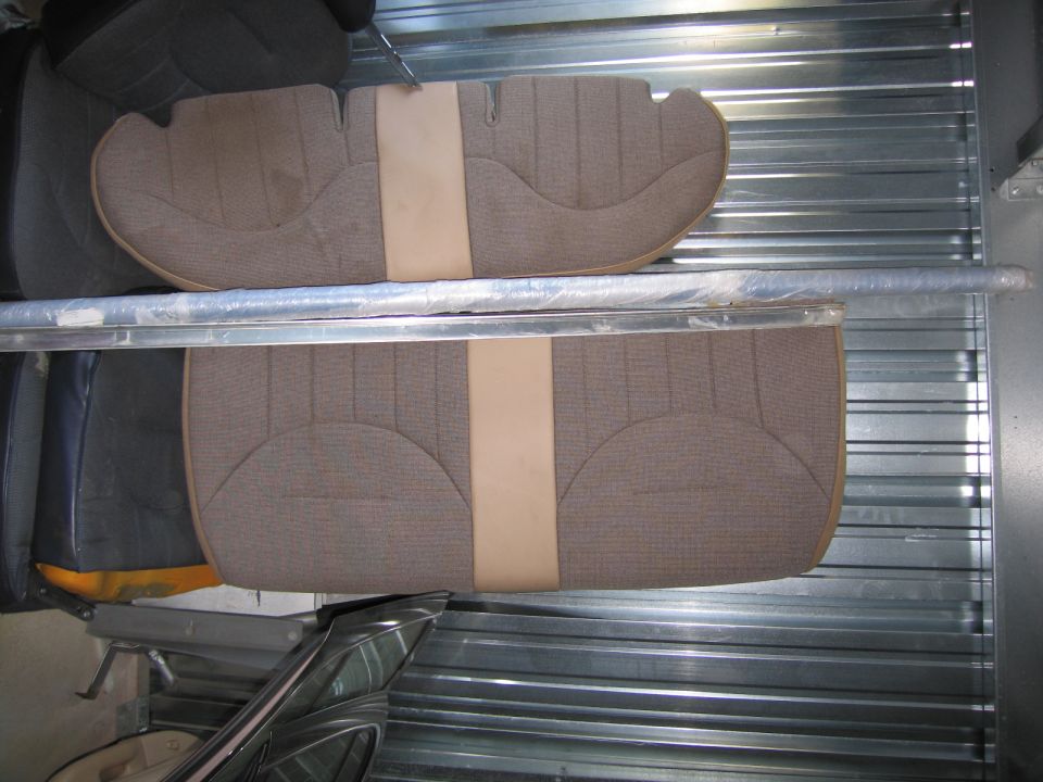 Two sections of car seat upholstery, brown with a tan stripe, stacked in a storage unit