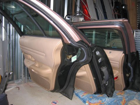 1991 Ford LTD Crown Victoria - The interior of a car is shown with both front and rear doors open, revealing the tan door panels and black door frames.