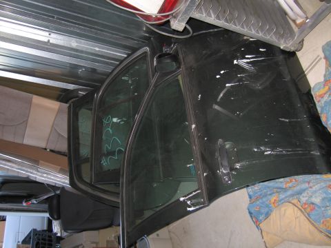 1991 Ford LTD Crown Victoria - A detached car door with visible markings on the window is stored indoors.