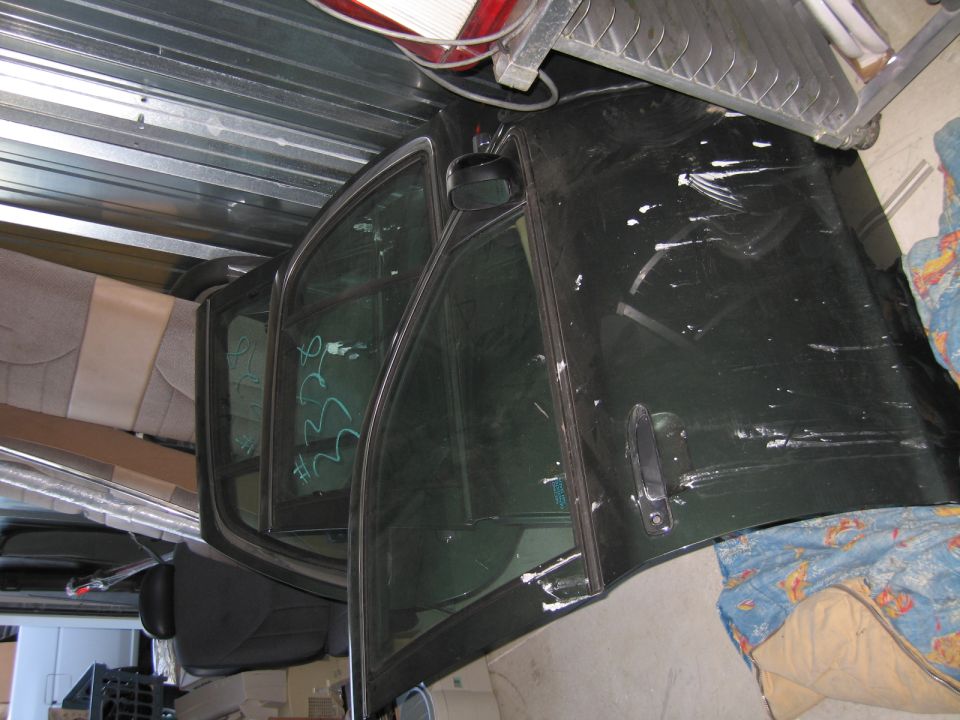 Dark green car door with white scuffs and a black door handle, seen from the side