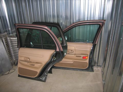 1991 Ford LTD Crown Victoria - The doors of a car, likely a sedan, are open, revealing the tan interior panels and tinted windows.