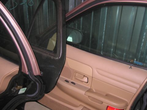 1991 Ford LTD Crown Victoria - The interior of a car shows the tan door panels and the open front door, revealing the rear door panel.