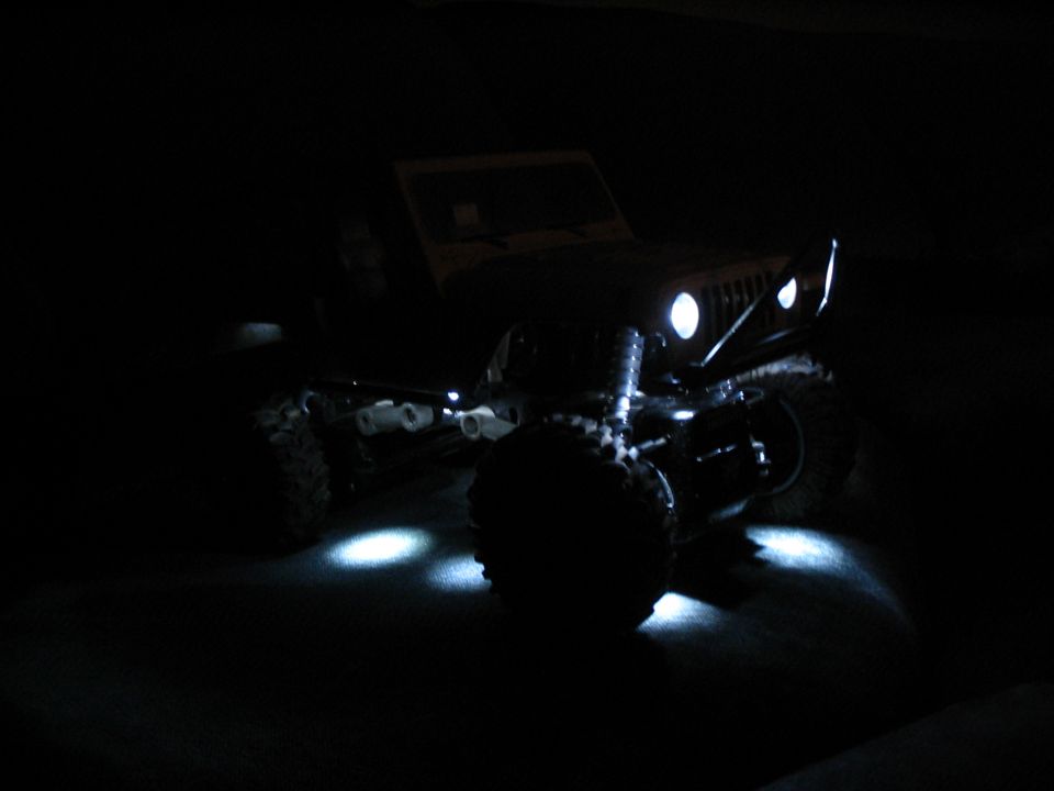 RC crawler at night with bright white LED headlights and underbody lights glowing in the dark