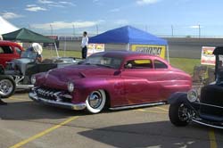 1972 Ford Ranchero - A customized purple coupe with whitewall tires is parked outdoors, with other vehicles and tents visible in the background.