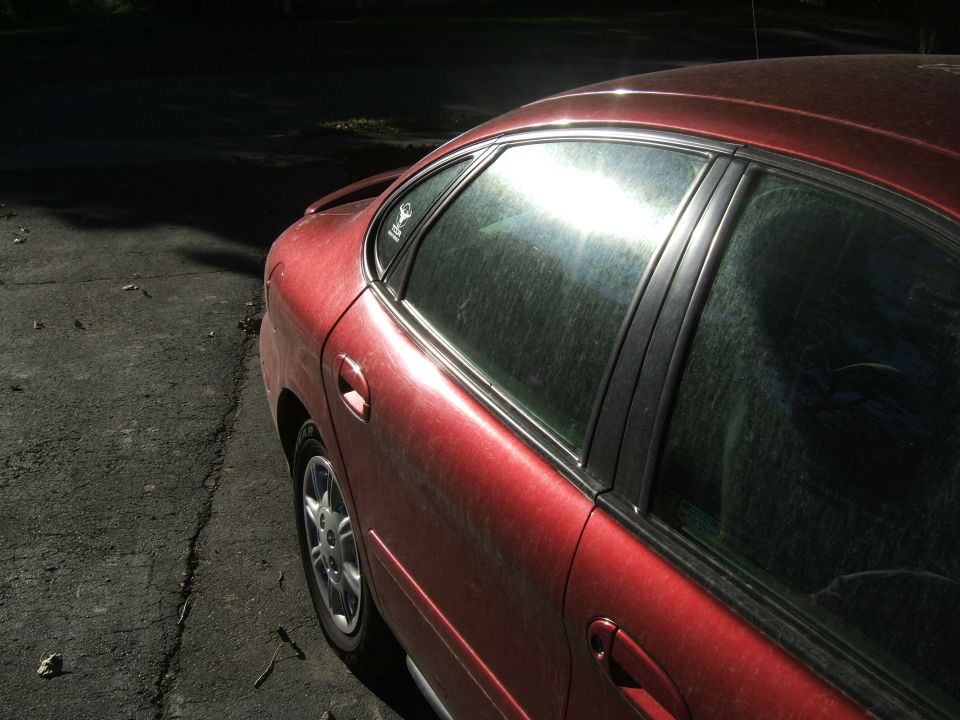 Red 1998 Ford Taurus sedan, side view, sun glare on windows