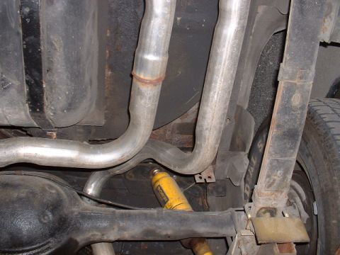 1978 Ford Mustang II - Underside view shows exhaust pipes, rear axle, fuel tank, and shock absorber. Text 'SUPERMOTORS' is visible.