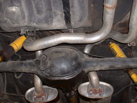 1978 Ford Mustang II - The underside of a vehicle shows the rear differential, fuel tank, and dual exhaust system with yellow shock absorbers.