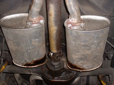 1978 Ford Mustang II - Underside view of dual exhaust mufflers and driveshaft, with visible rust and fluid leaks.