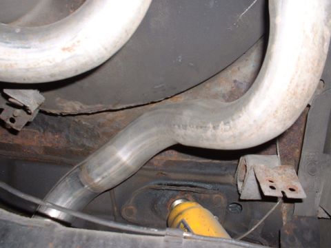 1978 Ford Mustang II - Close-up of the vehicle's exhaust system, showing metal pipes and rusted undercarriage components.