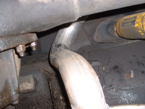 1978 Ford Mustang II - Close-up view of vehicle undercarriage components, including an exhaust pipe and a yellow shock absorber.