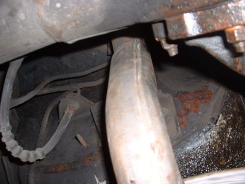 1978 Ford Mustang II - Underside view of vehicle exhaust pipe and brake line, showing rust.