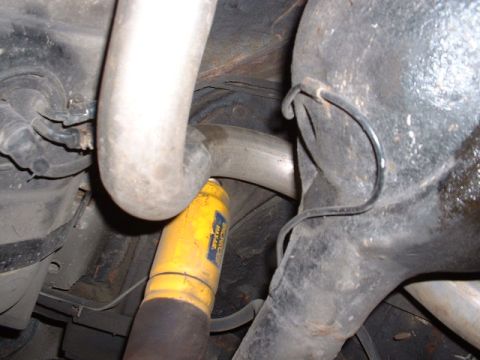 1978 Ford Mustang II - Underside view of a vehicle's exhaust system and a yellow shock absorber with visible text.