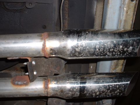 1978 Ford Mustang II - Close-up view of the underside of a vehicle, showing two chrome exhaust pipes with signs of rust and pitting.