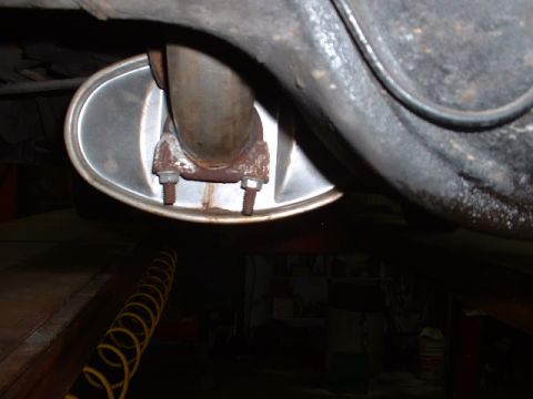 1978 Ford Mustang II - The underside of a vehicle shows a rusty exhaust pipe connected to a muffler with two bolts.