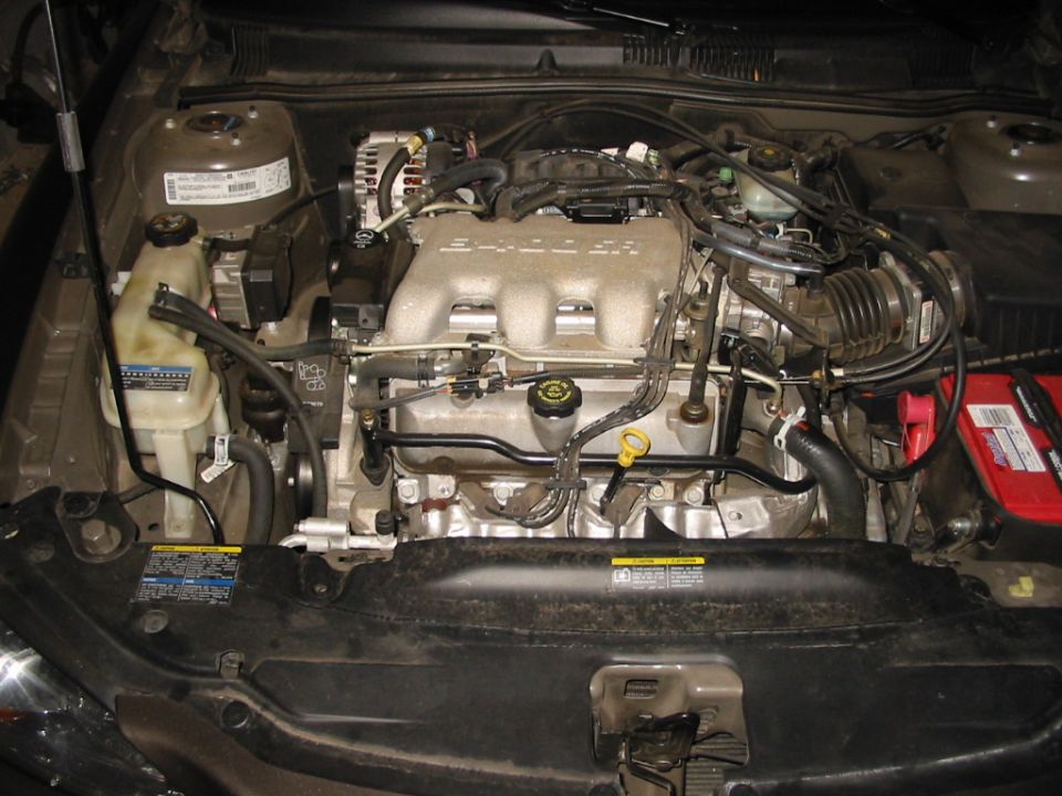 GM 3400 SFI V6 engine bay with coolant reservoir and red battery