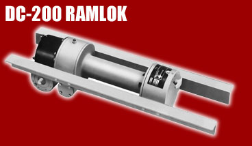 1985 Ford Bronco - A DC-200 Ramlok winch is shown mounted on a metal rail system against a red background.