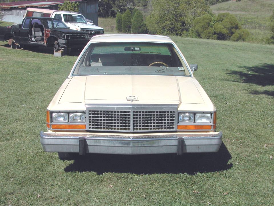 Cream-colored sedan front view. Grille and headlights visible