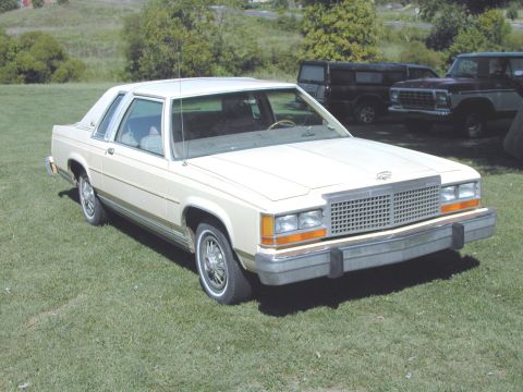 1985 Ford LTD Crown Victoria - Cream-colored 1985 Ford Crown Victoria LTD with a two-tone grille and chrome bumper.