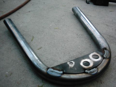 1978 Ford Bronco - A custom metal part, possibly for a vehicle project, lies on a concrete surface.