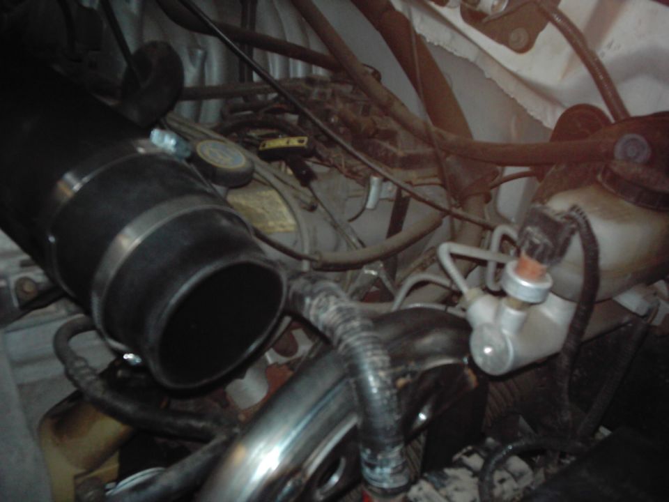Engine bay with large intake tube and various hoses and components visible