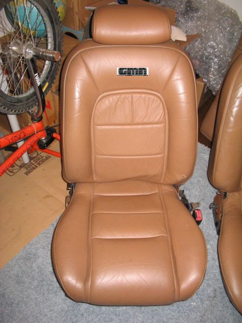 1997 Ford Crown Victoria - A tan leather car seat is shown, with a black emblem on the headrest area.