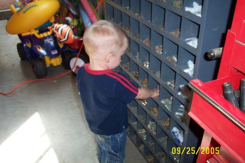 1995 Ford F-350 - A young child browses through a parts bin in a garage, with a toy vehicle in the background.
