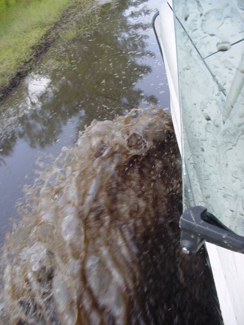 1989 Ford Bronco - A vehicle drives through a flooded area, creating a large splash.