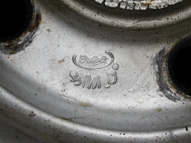 Close-up of Ford script and code stamped into the center of a silver steel wheel
