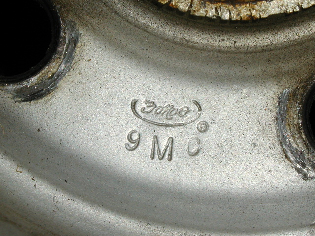 Ford oval and 9MC casting code stamped into a bare steel wheel center