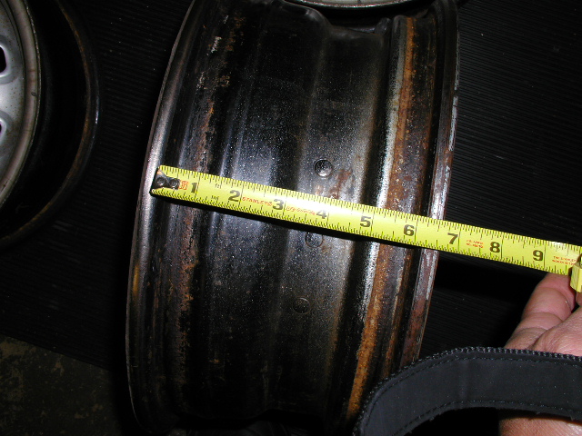 Tape measure across a bare steel wheel barrel checking rim width